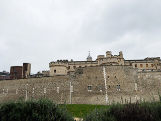 Tower of London fortress with medieval stone walls and towers along the moat in central London, UK under an overcast sky © AS Photo Family