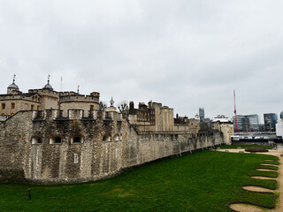 Fototapeta premium Tower of London historic fortress and medieval castle with moat and modern skyline in London, UK on an overcast day