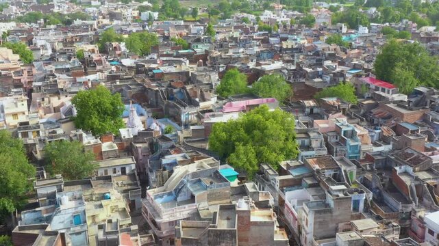 Tightly clustered rooftops and winding lanes form a dense neighborhood with scattered trees, reflecting compact living patterns in Ranakpur Sadri, Rajasthan.