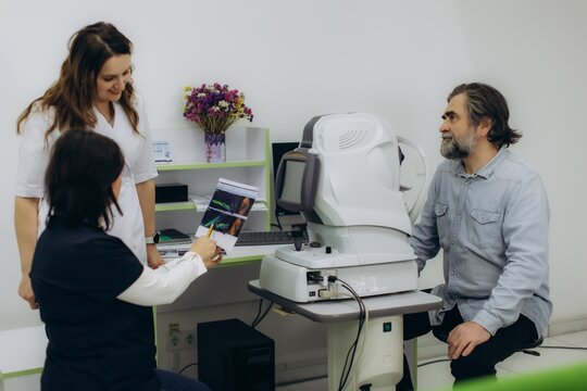 Patient receiving eye exam from ophthalmologist, reviewing vision test results