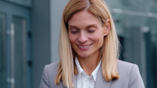 Close-up smiling Caucasian middle-aged business woman holding mobile phone in city smile happy enjoying smartphone businesswoman reading good news female enjoy cyberspace technology pause outdoors