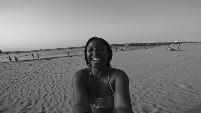Happy young african woman smiling on camera during summer beach vacation - Black and white editing - UGC content