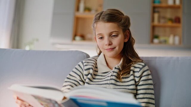 Smart kid flipping fairytale resting sofa closeup. Little child looking book