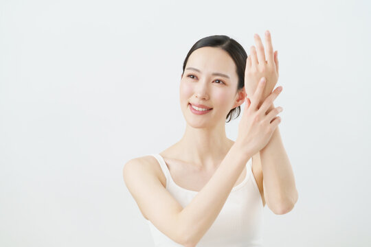 白背景の手のマッサージをする若い日本人女性