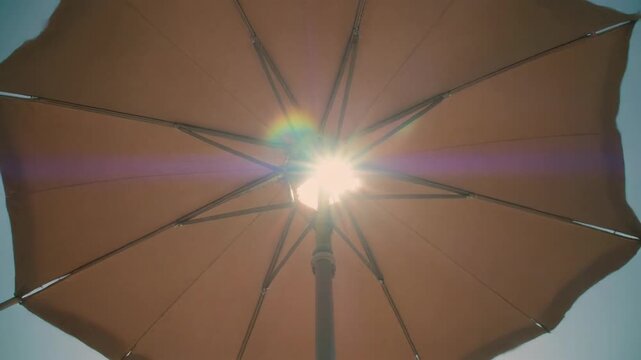 Sunlight peeking through a brown umbrella on a bright day. 4k Footage Video