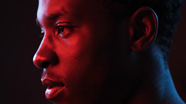 A serene male portrait is bathed in rich red light, casting a moody, atmospheric glow across a calm and contemplative face.