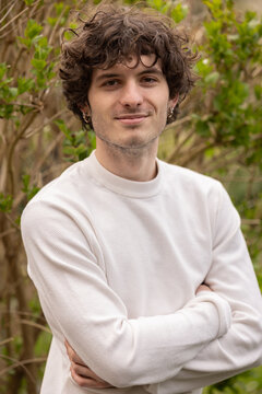 Portrait d&rsquo;un jeune homme de 20 ans en ext&eacute;rieur, affichant un sourire discret et une attitude confiante dans un environnement naturel apaisant.