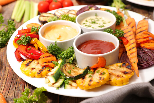 Grilled vegetable platter with dipping sauces, corn, carrots and bell peppers