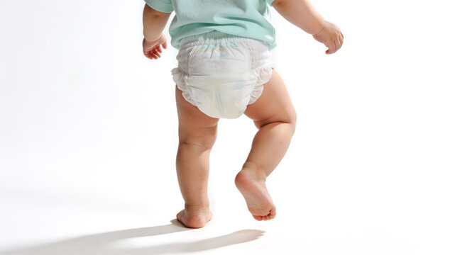 Close-up of a baby's legs and bottom wearing a white disposable diaper, walking on white background. Concept of childcare, hygiene, and infant development.