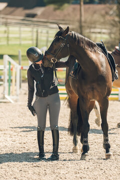 Equestrian athlete bonding with her horse in a dusty outdoor riding arena