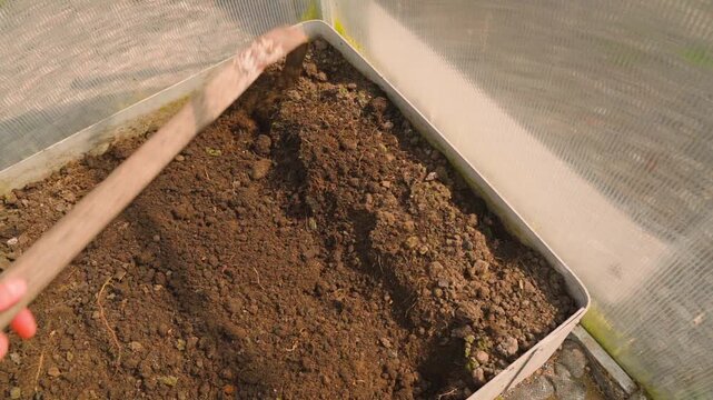 Tilling greenhouse soil with hoe slow motion top view