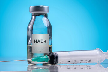 NAD plus vial with syringe on blue background anti aging concept