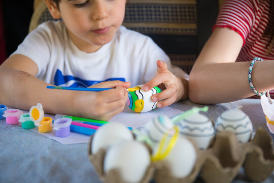 Caucasian child painting plastic Easter eggs, craft and art activity spring idea for kids.