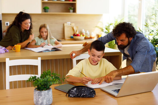 Family homeschooling children learning together in kitchen