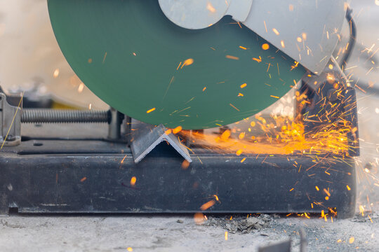 Worker cutting steel angle bar in construction site.
