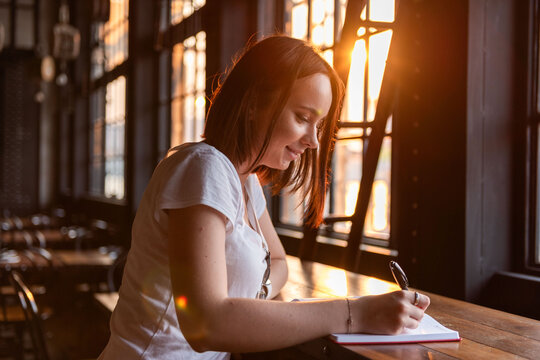 Woman writing in sunlight.