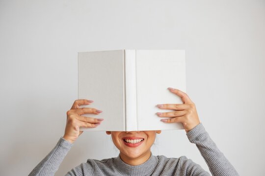 Smiling woman hiding behind book