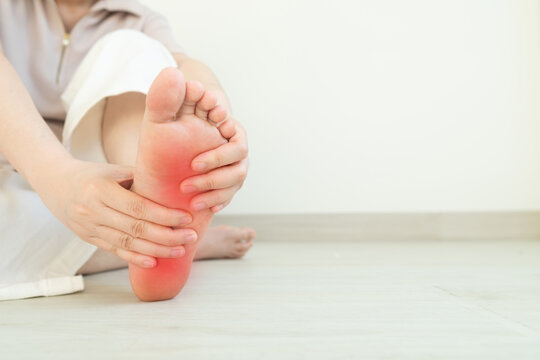 Female suffering from foot pain or numbness at home. Causes of pain include plantar fasciitis, gout, arthritis, tendinitis, diabetic neuropathy or overuse injuries.