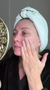Sad middle aged woman with acne and rosacea looking in mirror touching face, visible redness irritation skin problem, low self esteem insecurity and skincare concern concept