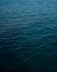 Obraz premium Vibrant Deep Ocean Water Surface. The image showcases a close-up of the ocean with varying shades of blue, and hints of light reflecting off the water surface