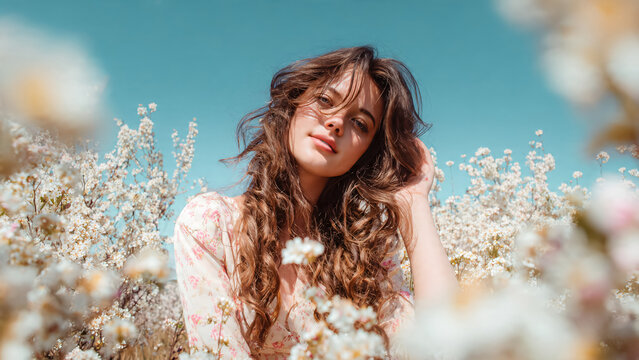 Jeune femme brune posant parmi les fleurs blanches