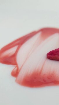 Spreading red or pink lip tint evenly on a white background using a brush. Abstract cosmetic art, bold pigment strokes, creative beauty concept isolated on clean surface.