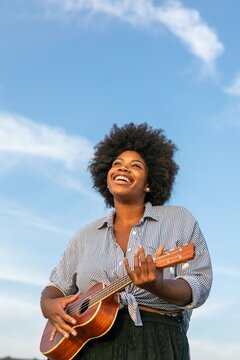 Joyful woman playing ukulele outdoors