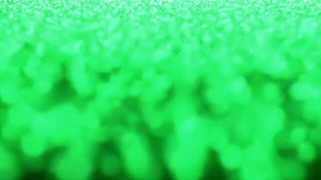 Magic green glitter particles falling from top against a dark background for festive celebration or emerald magical dust effect