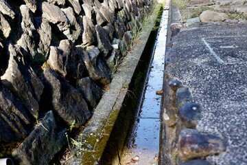 用水路と石垣・苔むした古い水路・田舎の農業用水 © umaruchan4678