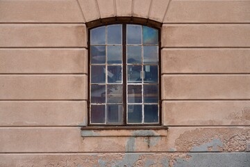 Fototapeta premium A large checkered window with arched top on the worn facade of a building at the navy museum in Horten, Norway.