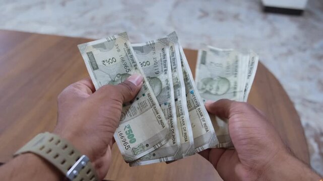 Close up of hands counting 500 rupee Indian currency notes
