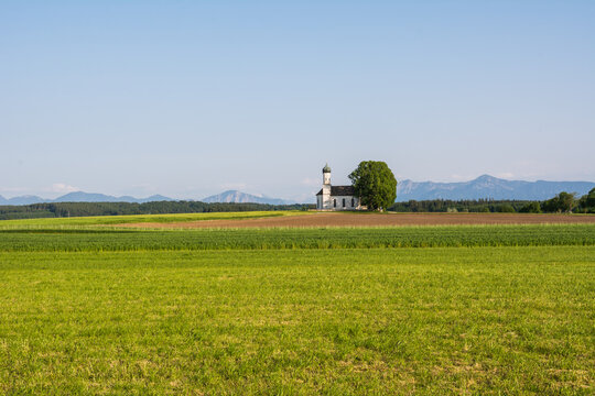 Traditional Bavarian chapel St. Andreas in Etting with a panoramic view of the Alps and green fields
