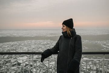 Fototapeta premium Woman on deck observing ice floes during sunset at a winter location near the water