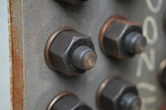 Industrial heavy duty bolts and nuts on a metal plate.