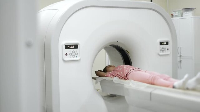 Wide view of CT scanner machine with child patient during diagnostic imaging in hospital radiology department.