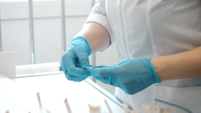 Medical worker in gloves removing pill from blister pack in clinic preparing medication for patient treatment.