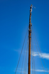 Fototapeta premium Tall sailing mast with detailed rigging against a clear blue sky. Symbolic scene for direction, ambition, resilience and maritime heritage, highlighting craftsmanship and nautical structure.