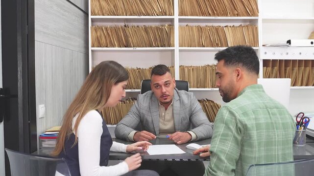 Young couple in conflict arguing about the terms of their divorce agreement. A lawyer or notary mediates the dispute at his office desk