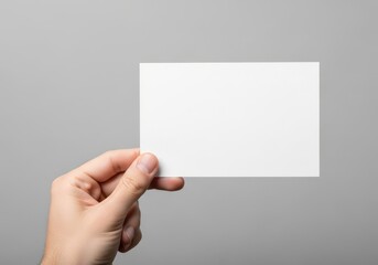 Obraz premium A close up view of a human hand holding a blank white rectangle card against a light grey background