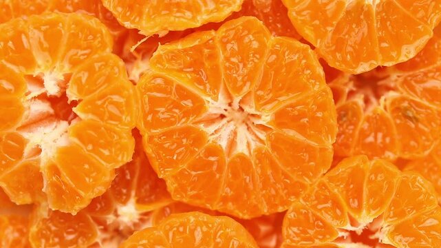 pile of halved small mandarin oranges pulp rotating slowly, top view shot.