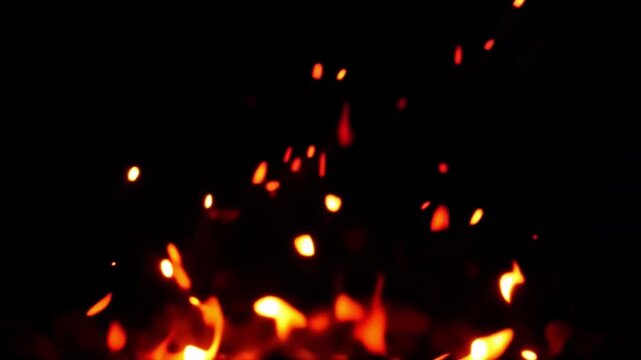 Glowing ember fire sparks burning coal with bright orange light dark background creating warm fiery glow heat energy motion and dynamic glowing particles flame firelight night hot coal burning ember