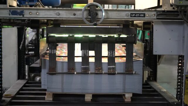 Metal sheets are moved on an industrial machine at a cap manufacturing plant.