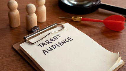 Target Audience list on clipboard with magnifying glass and wooden figures for market segmentation
