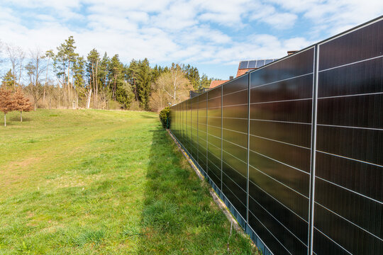 Vertical solar panel fence generating renewable energy along residential property boundary, modern photovoltaic system, sustainable technology, clean power solution