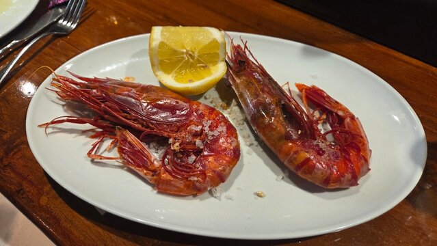 Spanish prawn tapas dish on a white plate with lemon and coarse salt for restaurant menu and food background photography. Carabinero, gamba carabinero, Aristaeopsis edwardsiana