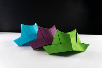 Obraz premium colorful origami paper hats in a row on a white surface.