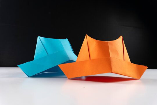 colorful origami paper hats in a row on a white surface.