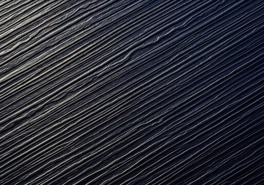 Detailed macro photograph of rough, dark plastic surface featuring deep, textured furrows, useful as an industrial background element, texture, plastic, grooved