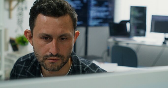 Caucasian Man Ensuring Network Security.Developer working at desk, analyzing network security. Man ensuring data protection, coding software for cyber defense, and managing digital systems.

