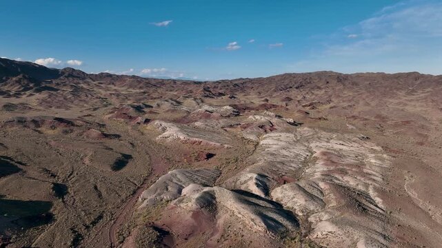 Drone video flying over brown volcanic mountains of Katutau in Altyn Emel National Park on a sunny day. Scenic aerial landscape of unique rock formations and wild nature.